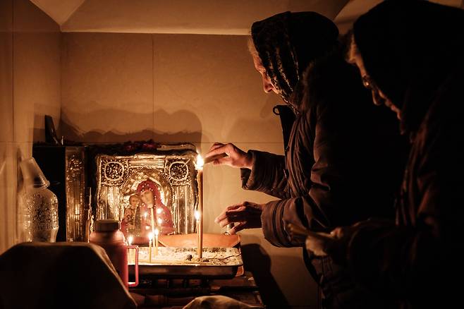 5일(현지시간) 러시아군의 포격이 계속되는 우크라이나 동부 바흐무트에 있는 한 교회 지하 시설에서 한 여성이 촛불을 켜고 있다. / 사진=AFP 연합뉴스