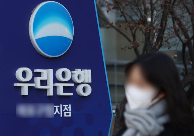 한 시민이 지난달 서울 시내의 한 우리은행 지점 앞을 지나고 있다. 연합뉴스