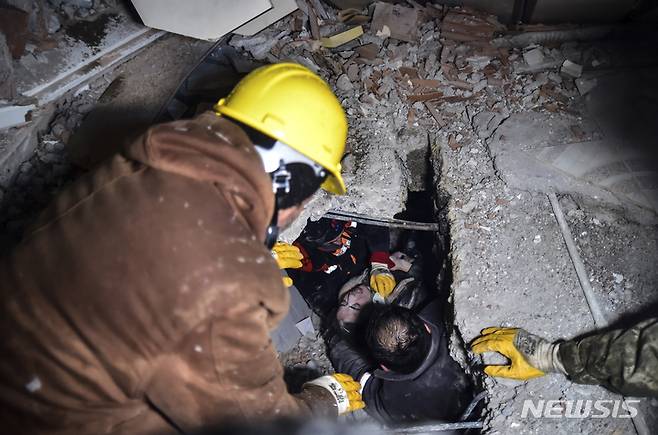 [카라만마라스=AP/뉴시스] 7일(현지시간) 튀르키예 남부 카라만마라스 엘비스탄에서 구조대가 지진으로 무너진 건물 잔해 속에 매몰된 한 여성을 구조하고 있다. 2023.02.07.