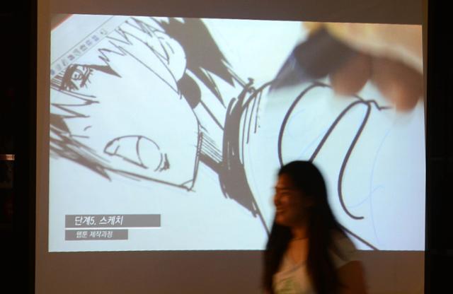 2014년 서울 서초구 반포동 국립중앙도서관 내 디지털도서관에서 진행된 웹툰 체험전(ALL Webtoon)에서 한 시민이 웹툰 작업 모습을 상영 중인 화면 앞을 지나고 있다. 홍인기 기자