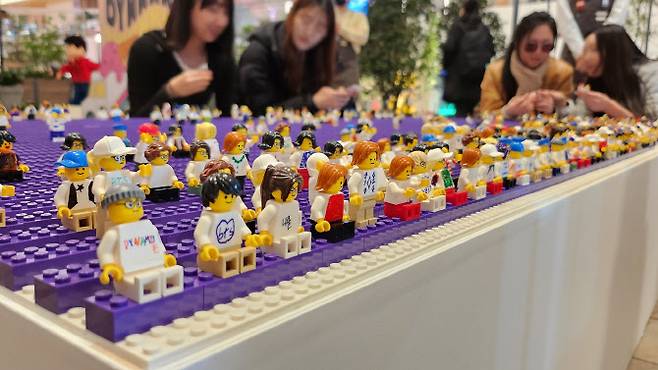 더현대 서울 ‘레고 BTS Dynamite 팝업스토어’에 마련된 BTS 콘서트 디오라마에 방문객들이 스스로 제작한 미니피겨를 관람객석에 앉혀놓고 있다. (사진=레고그룹)