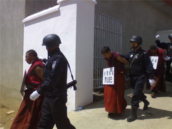 <2008년 4월 잡혀가는 티베트 승려들의 모습. 문화혁명 시기 적인(敵人, 인민의 적)을 모욕주고 처벌할 때 사용하던 팻말을 그대로 사용해서 승려들을 모욕하고 있다. 팻말에 적힌 네 글자는 “분열 국가,” 곧 국가를 분열시켰다는 죄명을 적어 놓았다. 사진/wikipedia.org>