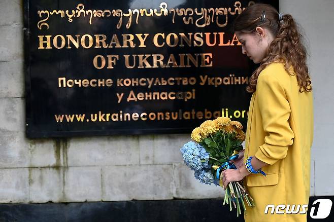 2월24일(현지시간) 인도네시아의 휴양지 발리 덴파사르에서 한 여성이 러시아의 침공 1년을 맞아 우크라이나 영사관 앞에 헌화하고 있다. 2023.02.24/뉴스1 ⓒ AFP=뉴스1 ⓒ News1 김민수 기자