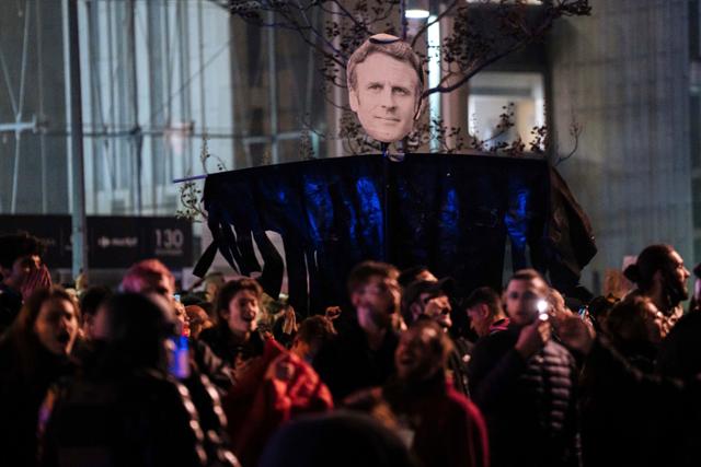 프랑스 파리에서 18일 연금개혁 반대 시위대 사이로 에마뉘엘 마크롱 대통령 얼굴이 보인다. 파리=AP 연합뉴스