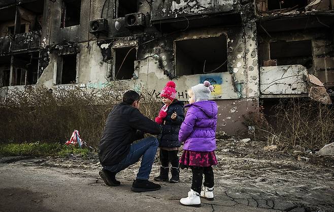 2022년 11월 9일 우크라이나 키이우의 보로디안카시의 파손된 건물 앞에서 한 남성이 아이들을 돌보고 있다. 게티이미지