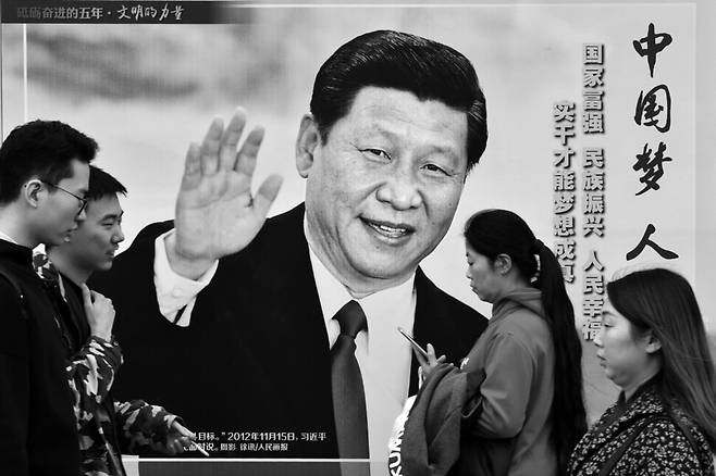 2017년 시진핑과 그의 구호인 ‘중국몽’을 선전하는 이미지를 담고 있는 큰 광고판 앞을 걸어 지나가는 베이징 사람들. 너머북스 제공