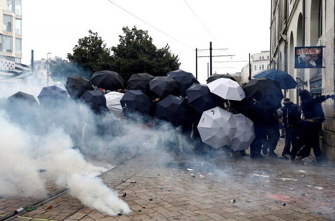 프랑스 연금개혁 반대 시위대가 23일(현지시각) 프랑스 낭트에서 시위 도중 경찰이 쏘는 최루탄을 막기 위해 우산을 펼쳐들고 있다. 낭트/로이터 연합뉴스