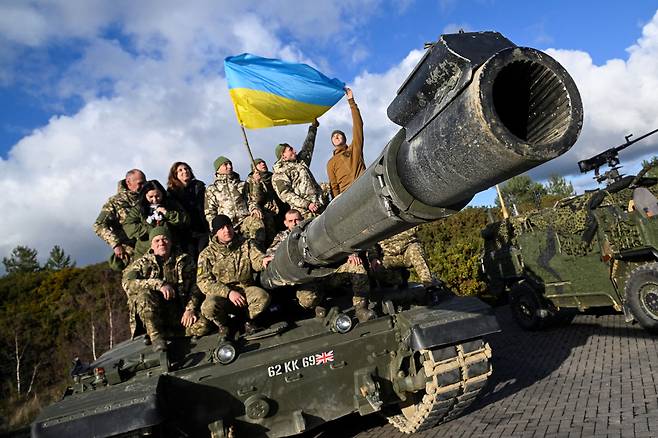 우크라이나 군인들이 2023년 2월22일(현지시간) 영국 남서부 울 인근 보빙턴 캠프에서 훈련 중 챌린저2 전차 위에서 깃발을 들고 포즈를 취하고 있다. / 사진=로이터 연합뉴스