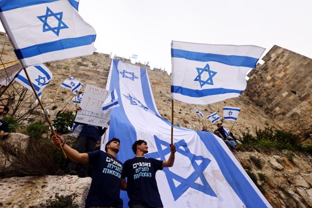 베냐민 네타냐후 이스라엘 총리가 강행하는 사법개혁에 반대하는 시민들이 23일 예루살렘 올드 시티 벽에 대형 국기를 내걸고 시위를 벌이고 있다. 로이터 연합뉴스