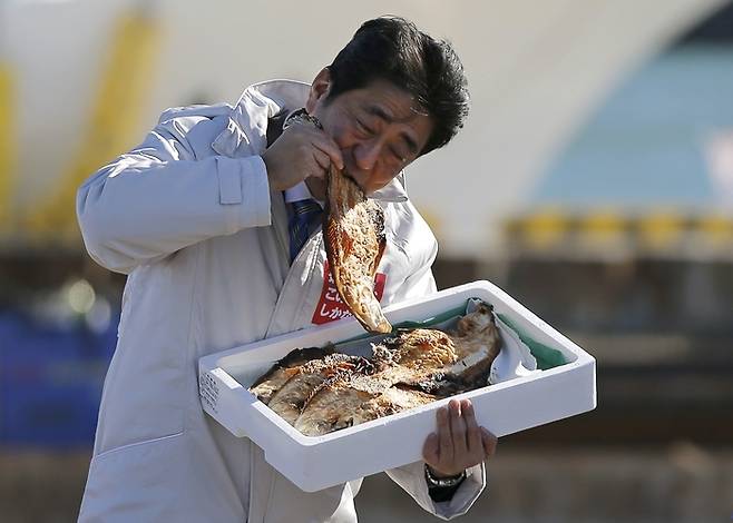 일본 중의원 선거 유세가 시작된 2014년 12월 2일 아베 신조 총리가 후쿠시마현 소마의 항구에서 생선구이를 시식하고 있다. 연합뉴스