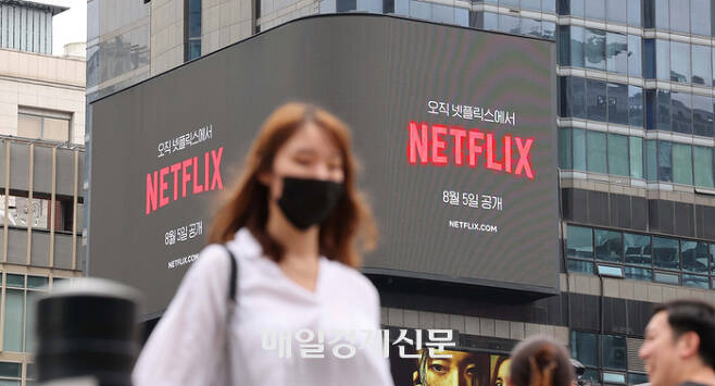 서울 강남역 일대 넷플릭스 옥외 광고판 앞을 시민들이 지나고 있다. <한주형기자>
