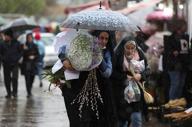 이란 여성들이 지난달 16일(현지시간) 비가 내리는 테헤란 시내 꽃 시장을 걸어가고 있다. 로이터연합뉴스