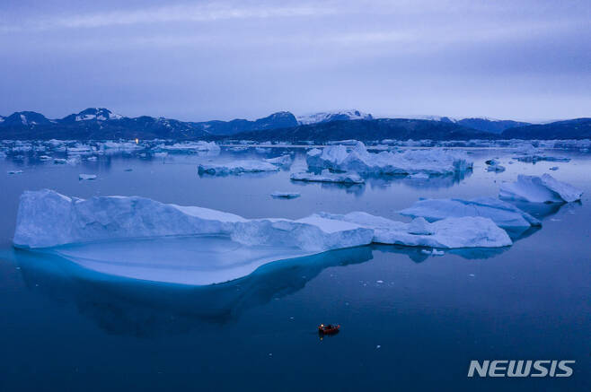 [쿨루수크(그린란드)=AP/뉴시스]2019년 8월15일 밤 그린란드 동부 쿨루수크 마을 근처 큰 빙산 옆을 배 한 척이 항해하고 있다. 그린란드와 남극에서 1년 간 녹아 없어지는 빙상의 양이 30년 전에 비해 3배 이상에 달하는 것으로 새로운 포괄적인 국제 연구 결과 밝혀졌다. 2023.04.20.