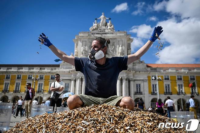 한 독일 환경운동가가 23일 포르투갈 리스본에서 65만개의 담배꽁초 위에 올라가 담배꽁초 투기 금지 시위를 벌이고 있다. ⓒ AFP=뉴스1 ⓒ News1 박형기 기자
