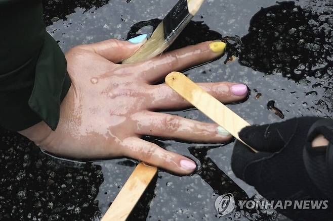 접착제로 아스팔트에 붙인 기후활동가의 손 떼어내는 경찰 / 사진=AP 연합뉴스