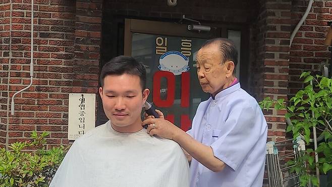 지난 13일 박정은씨가 이발사로서 마지막으로 망원동 주민 정민수(31)씨의 머리를 깎고 있다. 윤연정 기자