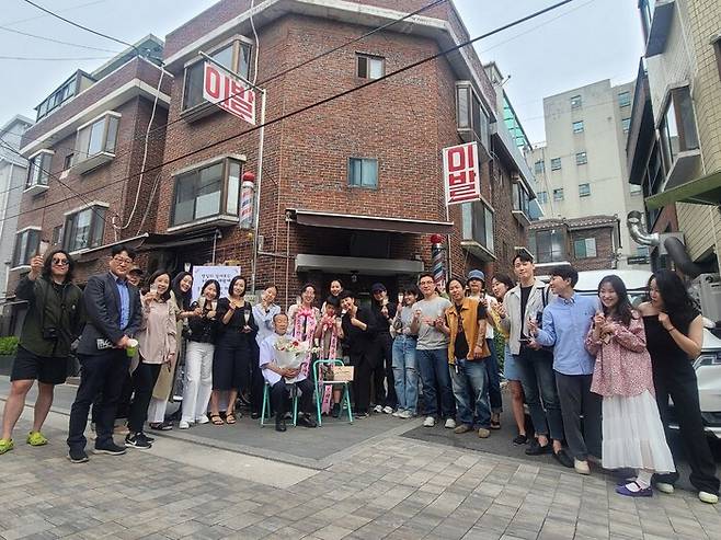 지난 13일 망원동 일흥이발소 앞에서 망원동 청년회와 지역 주민들이 박정은씨와 함께 기념 사진을 찍고 있다. 윤연정 기자