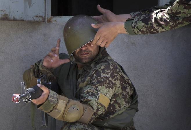 2013년 5월 훈련 중인 아프간 군 교육생의 방탄모를 조교가 바로 고쳐주고 있다. AP=연합뉴스