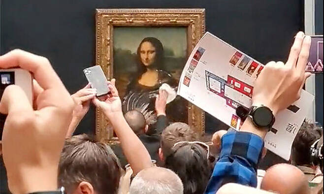 프랑스 파리 루브르 박물관에서 지난해 5월 29일(현지시간) 레오나르도 다빈치의 명작 모나리자 보호 유리에 케이크 크림이 묻은 모습을 관람객들이 촬영하고 있다. 파리=로이터연합뉴스