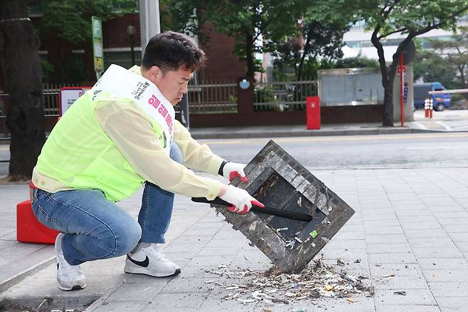 지난달 초 오언석 도봉구청장이 집중호우 때 배수가 잘되도록 하기 위해 빗물받이에 쌓인 담배꽁초 등 쓰레기를 치우고 있다. /도봉구 제공