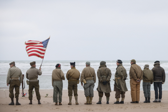 제2차 세계대전 노르망디 상륙작전 재연자들이 지난 6일(현지시간) 프랑스 노르망디의 생로랑쉬르메르에 있는 오마하 해변에서 성조기를 들고 서있습니다. AP 연합뉴스