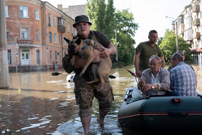 7일(현지시간) 우크라이나 남부 헤르손주의 홍수 지역에서 구조대원이 한 주민의 반려견 대피를 돕고 있다. / 사진=AFP 연합뉴스