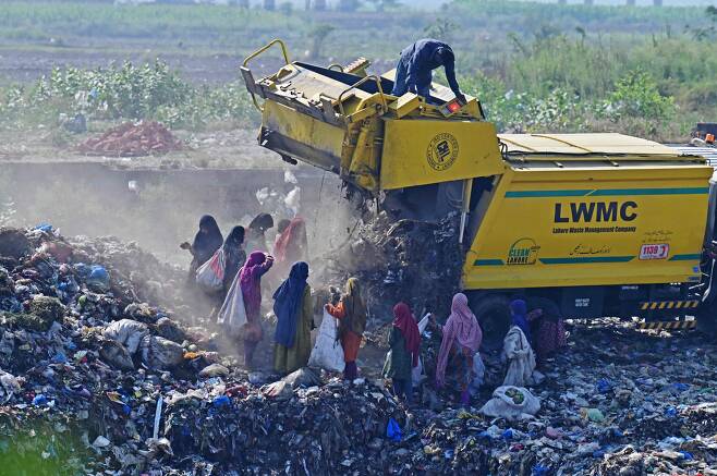 6월 5일 파키스탄 라호르 외곽의 한 쓰레기장에서 청소차가 쓰레기를 쏟아 붓자 사람들이 재활용이 가능한 물건을 줍기위해 몰려들고 있다./AFP 연합뉴스