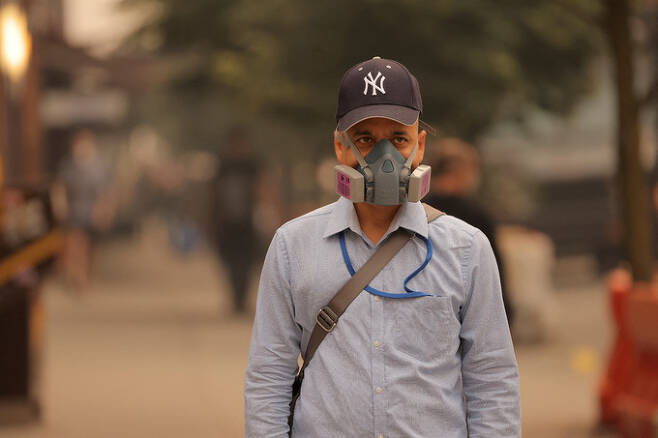 캐나다에서 발생한 산불 연기가 미국의 동부 지역까지 확산하는 가운데 7일(현지시간) 한 남성이 방진 마스크를 쓴 채 뉴욕 거리를 걷고 있다. 뉴욕 로이터=연합뉴스
