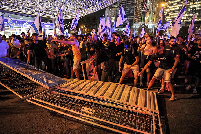 베냐민 네타냐후 정부의 사법부 권한 축소 입법 강행에 항의하는 이스라엘 시민이 24일(현지시간) 텔아비브에서 규탄 시위를 벌이며 경찰의 바리케이드를 무너뜨리고 있다. 이스라엘 의원은 반대 여론에도 불구하고 이날 해당 법안을 찬성 64표, 반대 0표로 가결했다. [AFP = 연합뉴스]