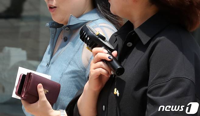 서울의 낮 최고기온이 35도까지 오르는 등 올들어 가장 무더운 날씨를 보인 19일 서울 중구 명동 거리에서 시민들이 휴대용 선풍기를 사용하며 이동하고 있다. 2023.6.19/뉴스1 ⓒ News1 김성진 기자