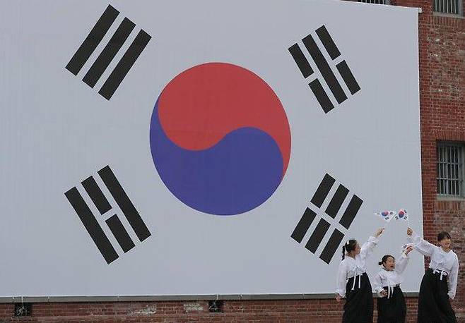 제78회 광복절을 하루 앞둔 2023년 8월 14일 낮 서울 서대문형무소역사관 벽에 게양된 대형 태극기 앞에서 학생들이 태극기를 들고 퍼포먼스하고 있다./뉴시스