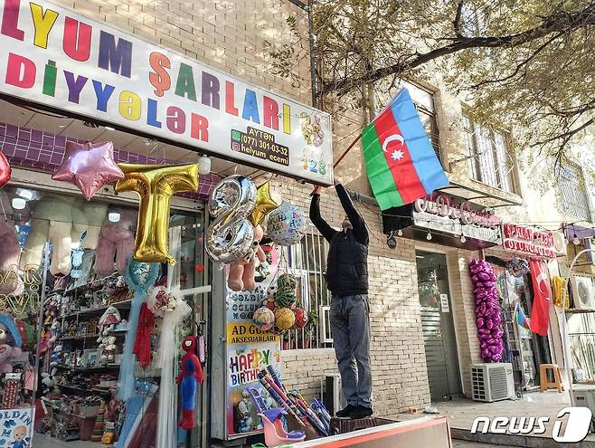20일(현지시간) 아제르바이잔 수도 바쿠에서 한 주민이 나고르노-카라바흐 지역에서 국가의 공세를 지지하는 뜻으로 가게 앞에 국기를 걸고 있다. 23.09.20 ⓒ AFP=뉴스1 ⓒ News1 김예슬 기자