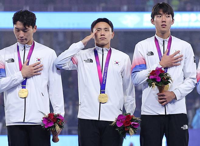 조영욱(가운데)이 지난 7일 중국 항저우의 황룽 스포츠 센터 스타디움에서 열린 남자 축구 결승전에서 2-1로 승리한 뒤 시상식에서 거수경례를 하고 있다. 연합뉴스
