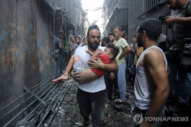 아이 안고 달리는 가자지구 팔레스타인 주민 (가자시티 AFP=연합뉴스) 팔레스타인 무장정파 하마스와 이스라엘군 간 교전 엿새째인 12일(현지시간) 가자지구 중심도시 가자시티에서 팔레스타인 남성이 아이를 품에 안은 채 달리고 있다. 지난 7일 하마스의 기습으로 교전이 시작돼 양측에서 지금까지 최소 2천400명이 사망했다. 2023.10.12 clynnkim@yna.co.kr