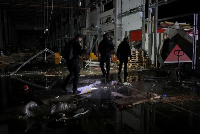 우크라이나 경찰이 22일 러시아의 미사일 공격을 받은 우크라이나 동부 하르키우주의 한 물류센터 현장을 조사하고 있다. 하르키우=로이터 연합뉴스