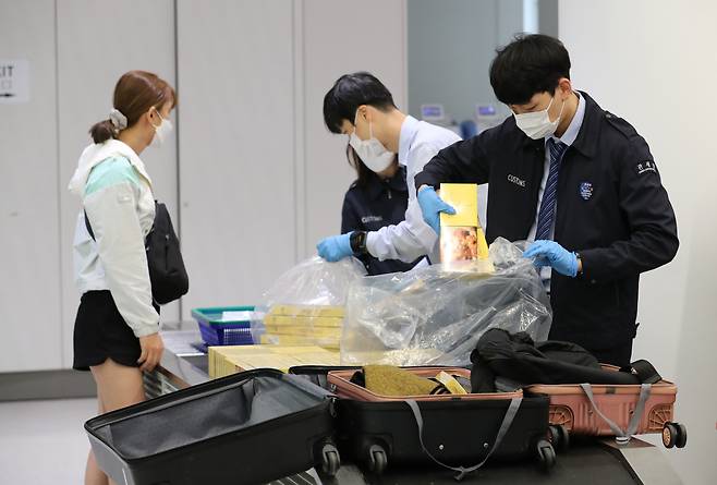 지난 18일 오전 인천공항 입국장 통관검사대에서 세관 직원들이 한 여성이 캐리어에 들고 온 밀수 담배를 꺼내고 있다. /남강호 기자