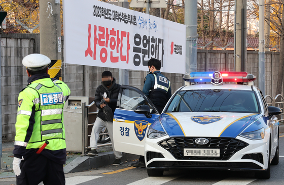 With police help, a test-taker arrives at the testing site at Yongsan High School in Yongsan District, central Seoul, on last year’s university entrance exam day, Nov. 17, 2022. [YONHAP]