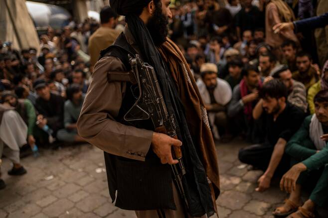 (카불 AP=연합뉴스) 아프가니스탄의 정권을 재장악한 탈레반의 한 대원이 12일(현지 시각) 수도 카불의 한 은행 지점에서 예금 인출을 기다리는 시민들을 통제하고 있다.