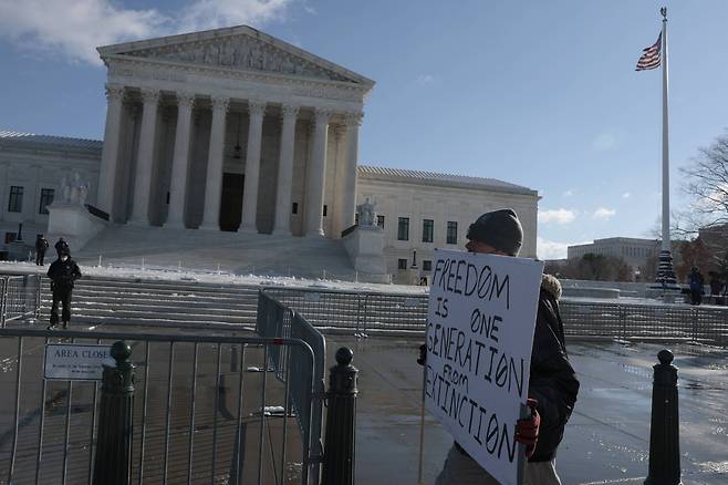 2022년 1월 7일(현지 시각) 미국 워싱턴 연방대법원앞에서 한 남성이 백신접종의무화에 반대하는 피켓시위를 하고 있다./AFP 연합뉴스