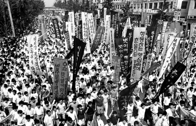 1987년 6·10민주항쟁 과정에서 숨진 연세대생 이한열 열사의 영결식이 열린 그해 8월 7일, 운구를 따라 깃발과 만장을 들고 행진하는 학생들의 모습. 민주화운동기념사업회 제공