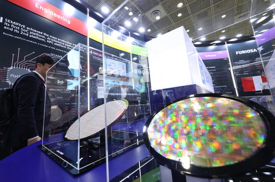 Visitors examine a semiconductor wafer at the Semiconductor Exhibition held at Coex, Gangnam, in October. [NEWS1]