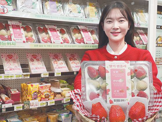 A woman holds a bucket filled with domestically produced strawberries at a 7-Eleven convenience store. [7-ELEVEN]