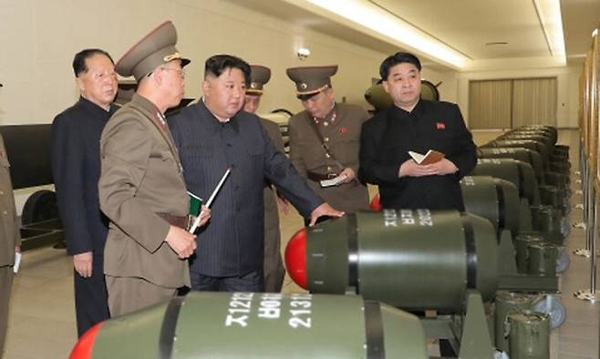 김정은 북한 국무위원장이 북한 핵무기 개발의 핵심조직인 군수공업부, 핵무기연구소, 미사일총국의 간부들과 함께 연구소를 찾은 가운데 새로 개발한 전술핵탄두 ‘화산31’을 둘러보는 모습. 조선중앙통신·연합뉴스
