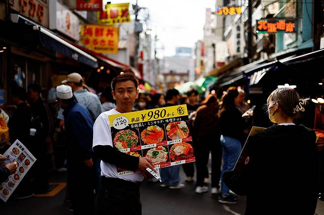 지난 15일 일본 도쿄의 쓰키지 장외시장에서 한 식당 직원이 메뉴를 들고 홍보하는 모습. 일본은 지난해 명목 국내총생산(GDP)이 독일에 밀리면서 경제 규모 4위로 내려앉았다. 엔저와 저물가 영향도 있었지만, 새로운 성장 동력을 찾아야 한다는 지적도 나온다. /로이터 연합뉴스
