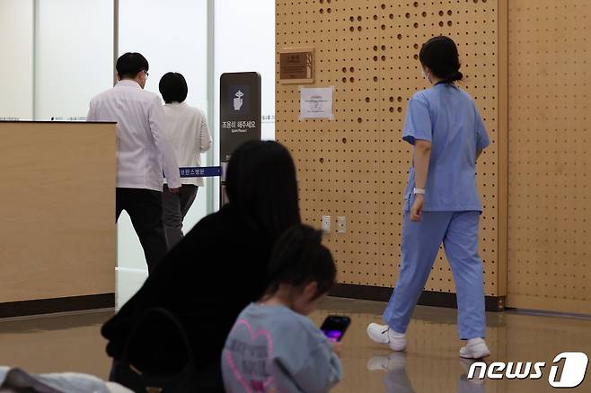 19일 오전 서울 서대문구 연세 세브란스 어린이병원에서 진료를 기다리는 어린이 가족 뒤로 의료진이 지나가고 있다. 2024.2.19/뉴스1 ⓒ News1 장수영 기자
