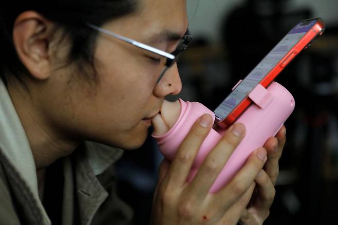3월 12일(현지 시각) 중국 베이징에서 한 남자가 원격 키스 장치인 "Long Lost Touch"를 시연하고 있다. /로이터 연합뉴스