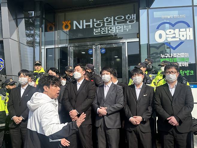 15일 서울 중구 농협은행 본점 입구를 보완요원들이 지키고 있는 가운데, 김태규 피해자모임 대외협력위원장이 발언하고 있다. ⓒ시사저널 정윤성