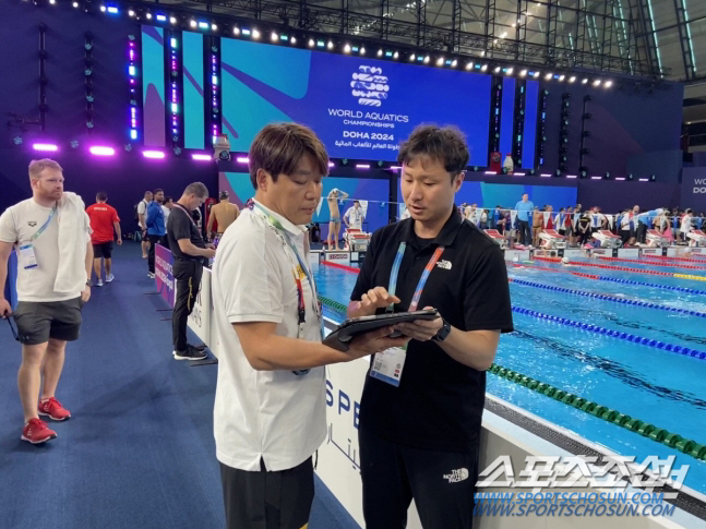전동현 수영대표팀 코치와 김형석 진천선수촌 영상분석관(과장)이 예선 영상 분석 데이터를 보며 의견을 나누고 있다