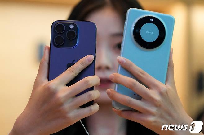 22일(현지시간) 아이폰15 시리즈 신제품 출시 첫날 중국 상하이의 애플 매장에서 고객이 아이폰 15 프로와 화웨이 메이트 60 프로와 비교를 하고 있다. 2023.09.22 ⓒ 로이터=뉴스1 ⓒ News1 우동명 기자