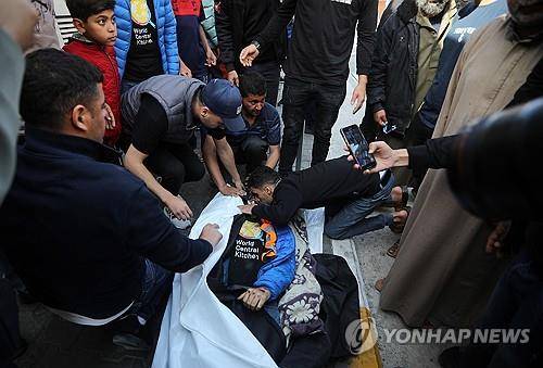 국제구호단체에 대한 이스라엘 오폭의 희생자 시신 옆에 모인 사람들 (UPI=연합뉴스)